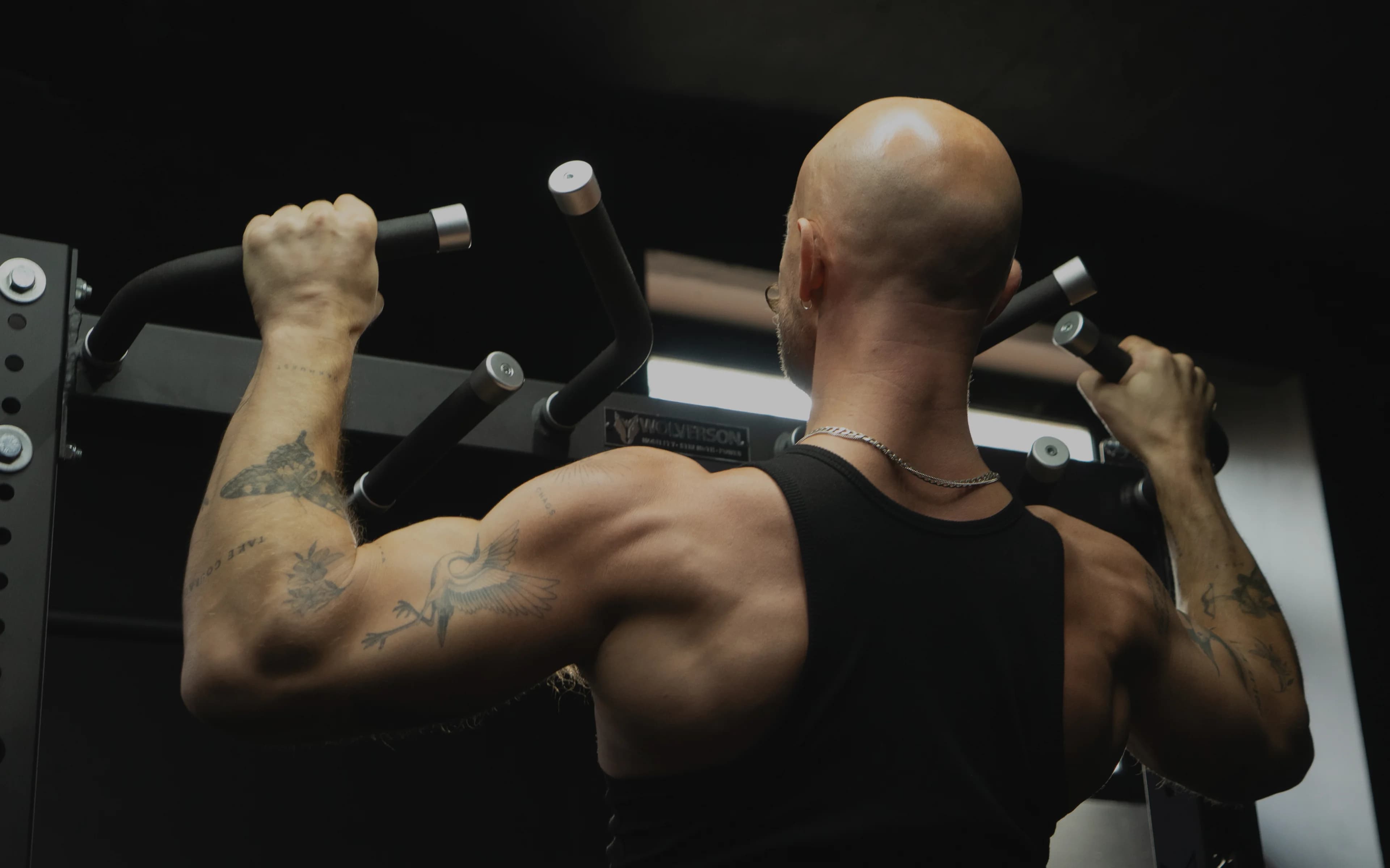 A Lift client performing a lat pulldown in a dimly lit gym, seen from behind.